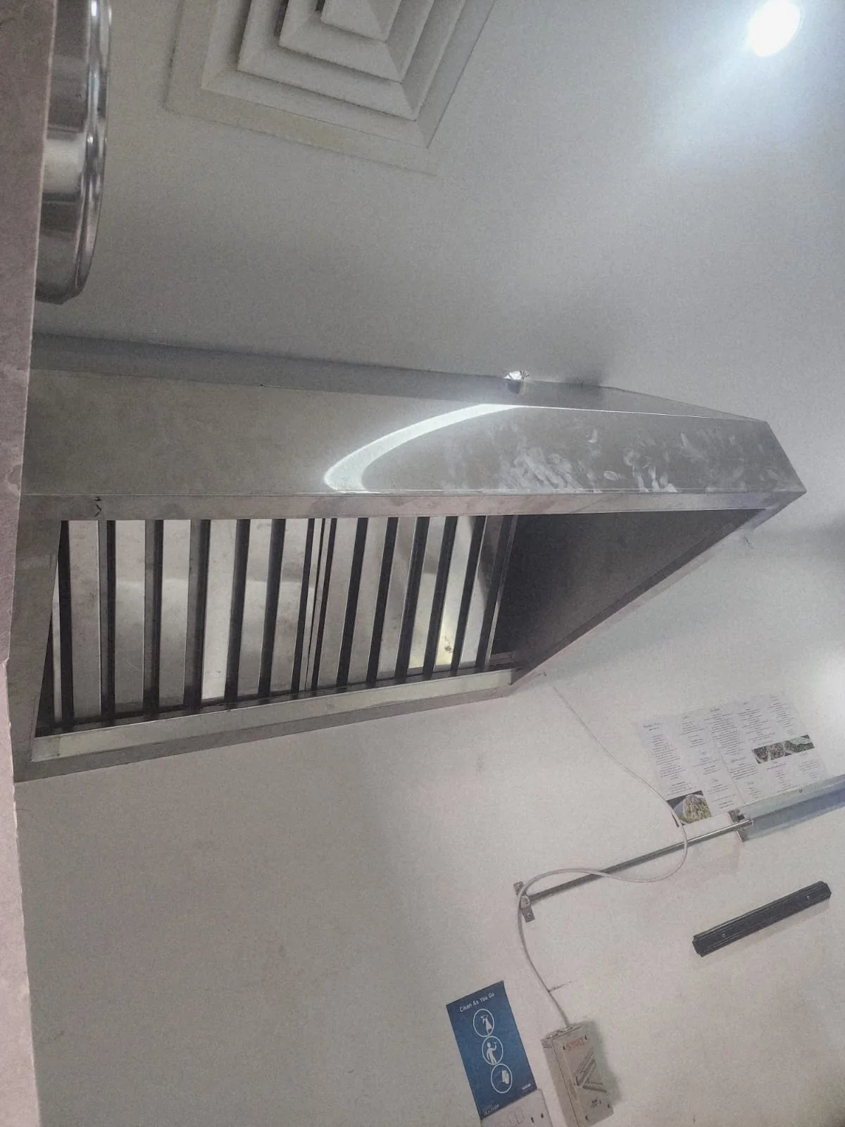 Underside view of an installed commercial kitchen hood and extraction assembly